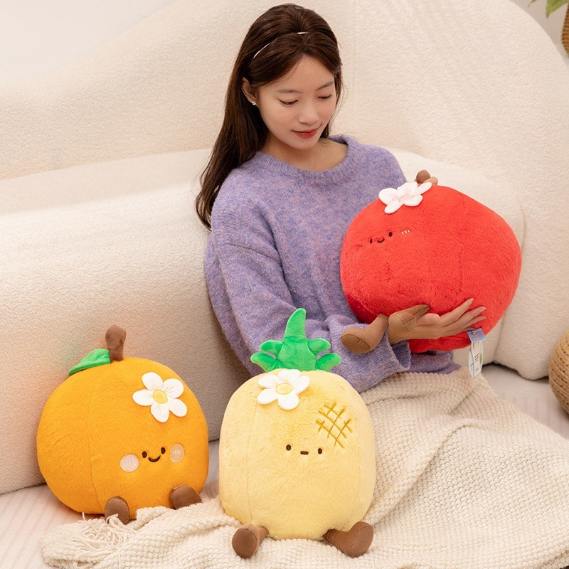 Cute fruit plush pillows in apple, orange and pineapple designs displayed on sofa for hugging and cozy home decor