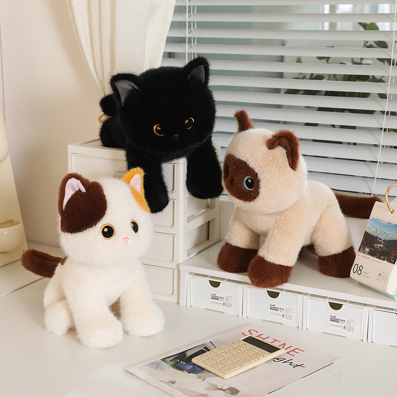 Poseable cat plush toys in black, calico, and Siamese designs arranged in sitting, standing, and lying poses on desk shelves in a cozy indoor setting