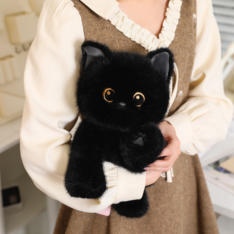 Black poseable cat plush toy with soft fluffy fabric and detailed eyes, shown as a cuddly companion in a warm indoor setting