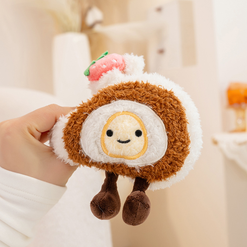 Original Swiss roll dessert plush toy with smiling face and soft layered design, held in hand in cozy home setting
