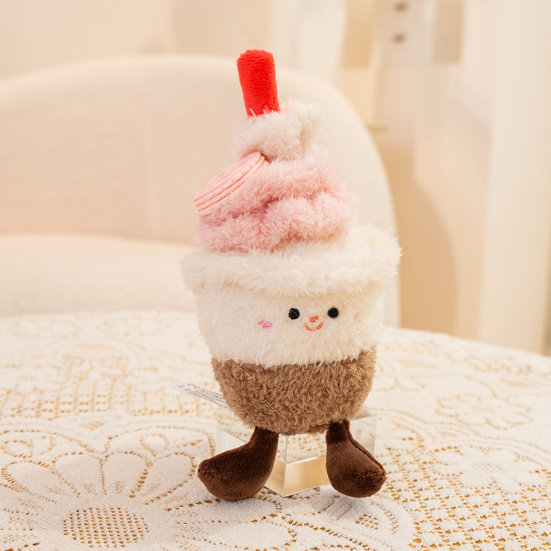 Cupcake dessert plush toy with pink frosting and macaron detail, soft plush fabric and small dangling legs, perfect for cozy bedroom decor or sweet themed gifts