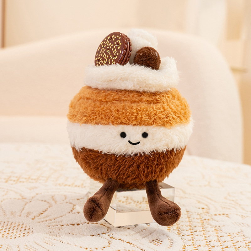 Macaron cake dessert plush toy with layered cream and chocolate macaron topping, fluffy round stuffed design displayed in a soft neutral interior for decorative use
