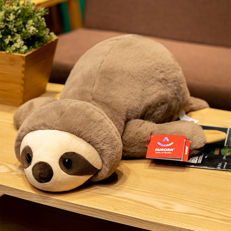 Sloth lazy lying plush toy resting on a wooden table, soft cuddly stuffed animal with relaxed posture for comfort and cozy spaces