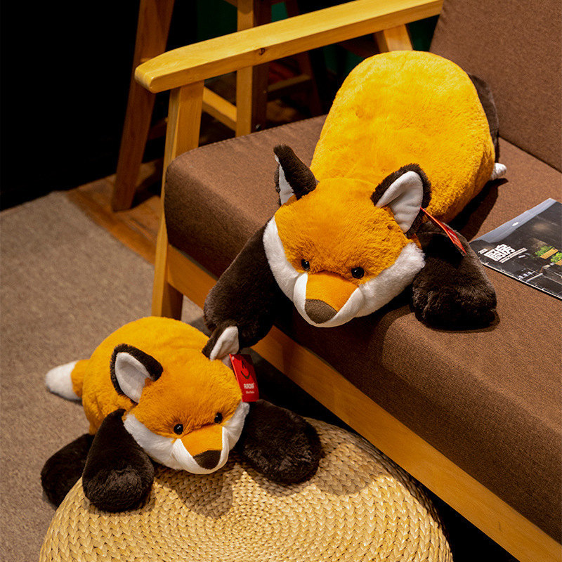 Fox lazy lying plush toys in two sizes on chair and woven stool, soft stuffed animals for cuddling and warm home styling