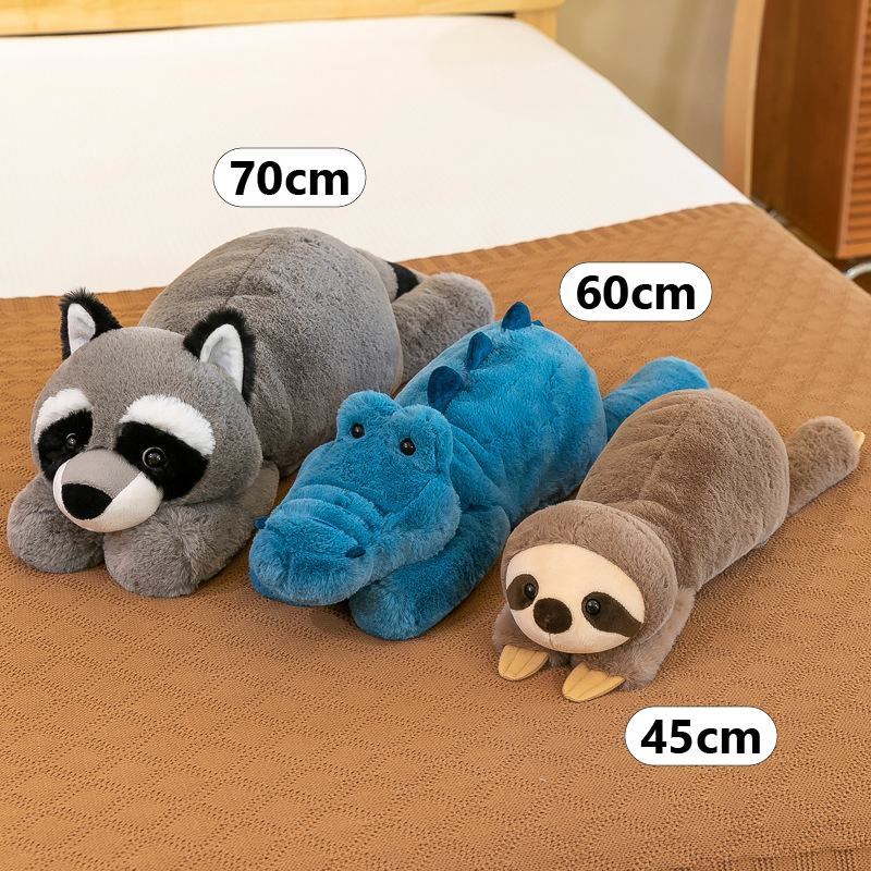 Lazy lying animal plush toys in 45cm, 60cm and 70cm sizes, featuring sloth, crocodile and raccoon designs displayed on a bed for size comparison