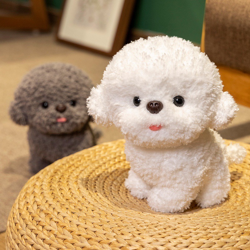 White Bichon Frise plush toy with fluffy teddy plush fabric sitting on woven mat, tongue-out soft stuffed dog design with gray version in background for home decor or gifting