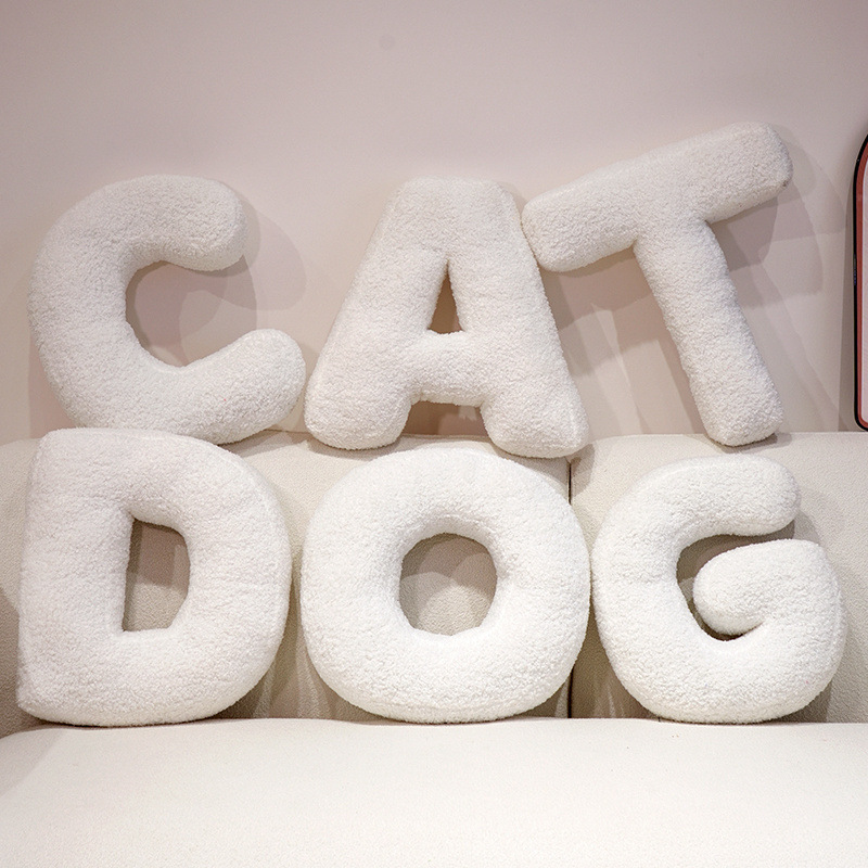 Alphabet plush pillows spelling CAT DOG arranged on a sofa, soft teddy plush letter cushions for personalized names and cozy living room decor