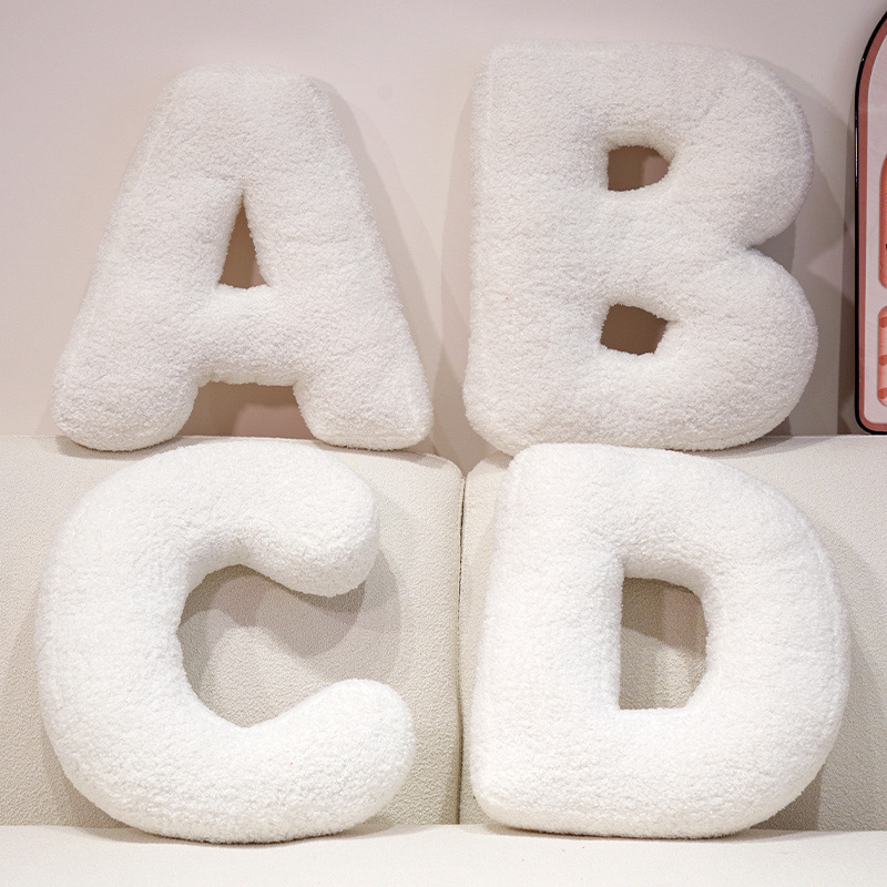 Alphabet plush pillows A B C D arranged on a sofa, soft teddy plush letter cushions for personalized names and cozy home styling