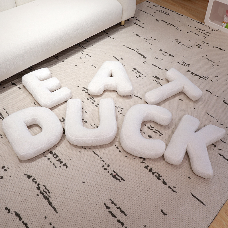 Teddy plush alphabet letter pillows arranged on a neutral rug, soft decorative cushions perfect for creating names or meaningful words
