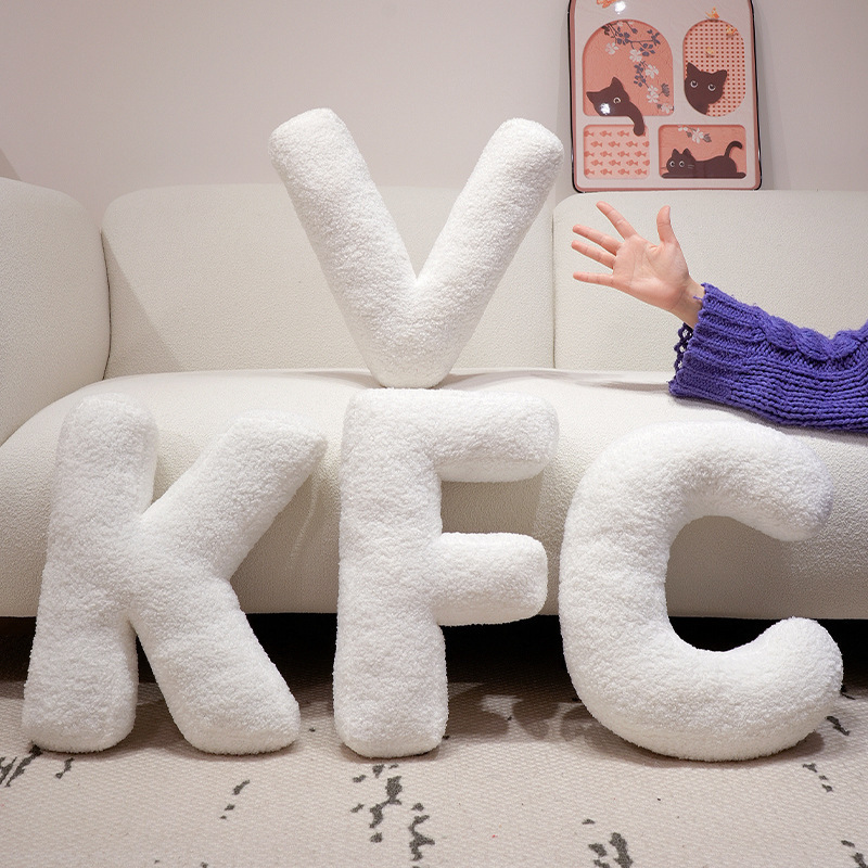 Alphabet plush pillows spelling VKFC displayed on a sofa, soft teddy plush letter cushions for cozy home decor and personalized styling