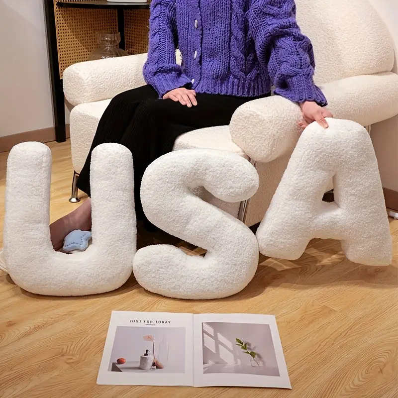 Soft teddy plush alphabet letter pillows spelling USA placed on the floor in a cozy living room, ideal for sofa and home decor styling