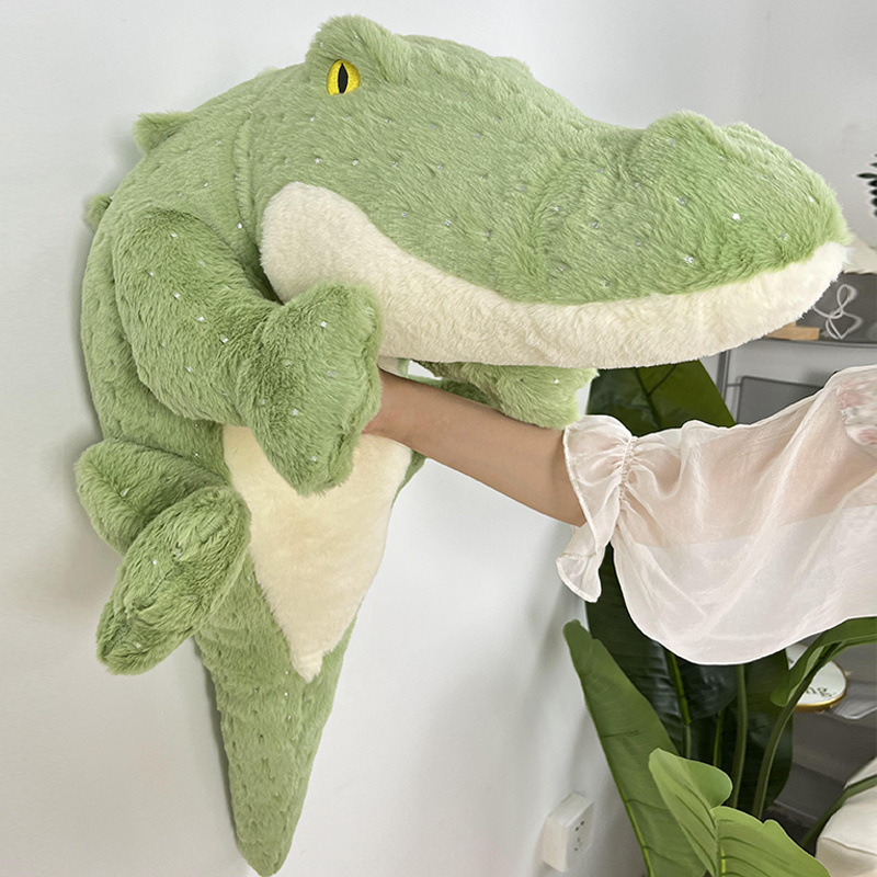 Crocodile plush toy gently pressed against wall, showing soft plush texture and flexible long body design