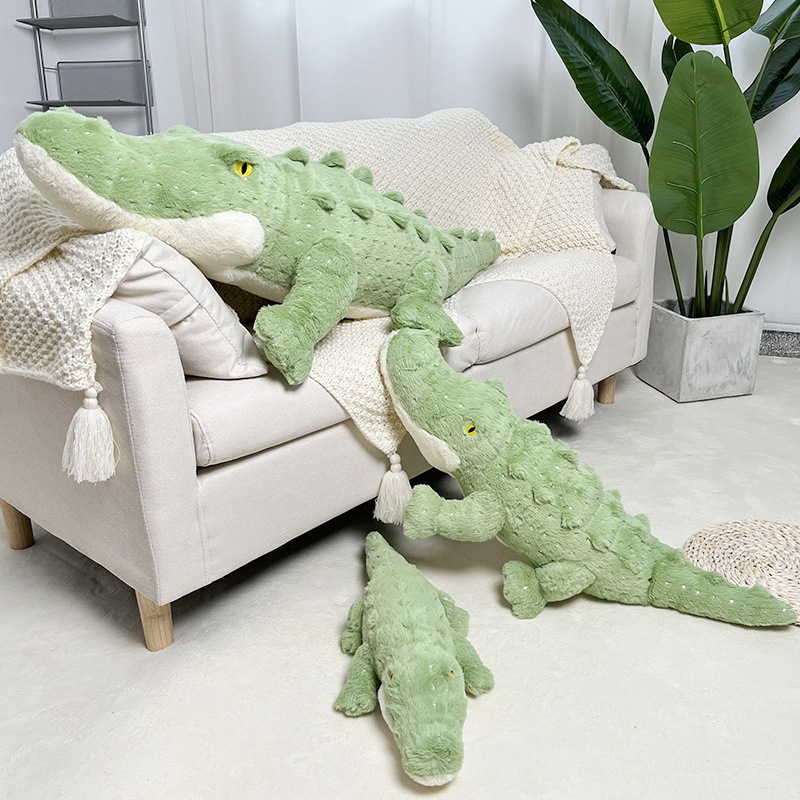 Crocodile plush toy in 55cm, 85cm and 115cm sizes displayed on sofa and floor, soft green long body stuffed animal for hugging and home decor