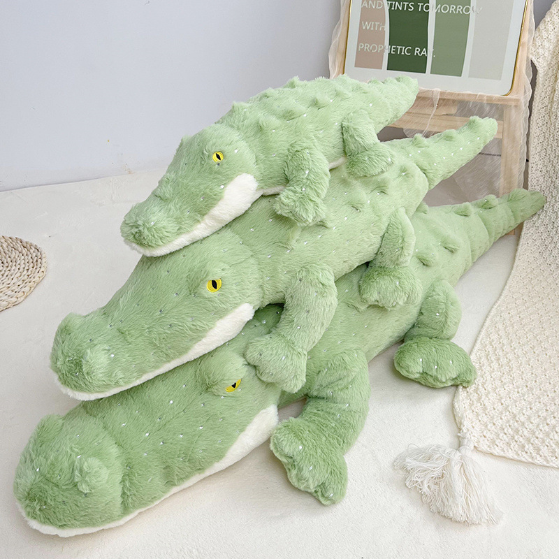 Green crocodile plush toy in multiple sizes stacked together showing soft texture and long body design