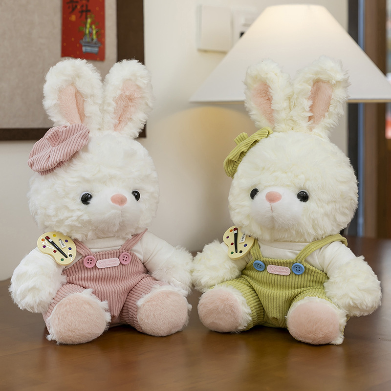 Mora bunny plush toys in pink and green outfits sitting on a wooden table, fluffy texture and warm indoor setting
