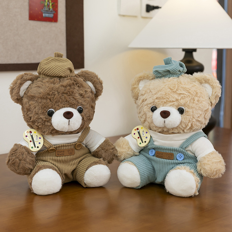 Mocha bear plush toys in brown and blue corduroy overalls sitting on a wooden table, cozy indoor decor setting with soft lighting