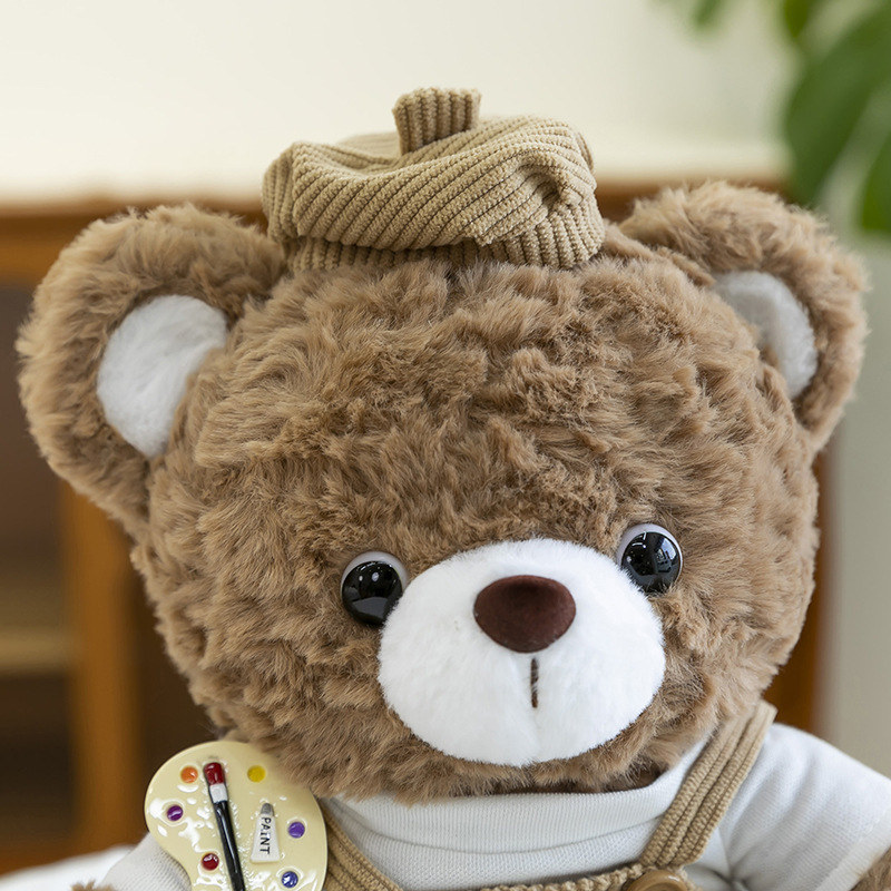 Close-up of mocha bear plush toy face with soft curly fur, glossy eyes and corduroy beret detail