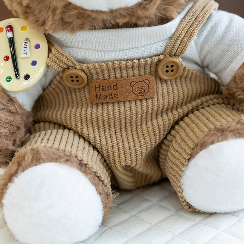 Mocha bear plush toy corduroy overalls close-up, featuring button details and handmade style label
