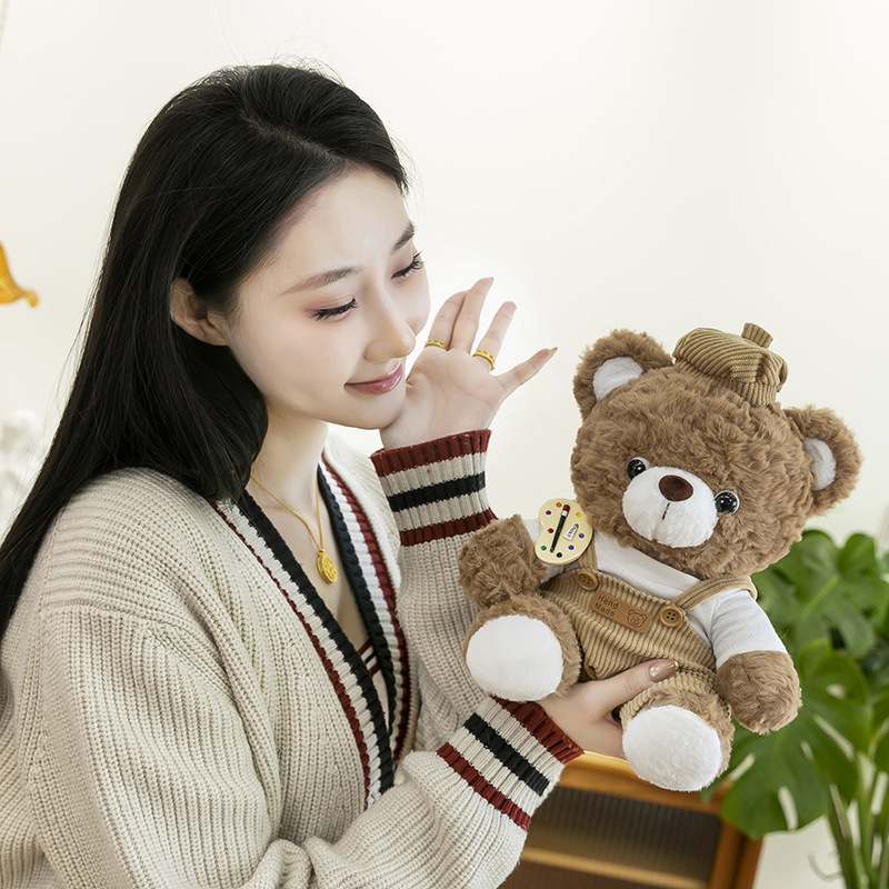 Mocha bear plush toy gently held for close-up view, highlighting fluffy fabric, beret hat and handmade style design