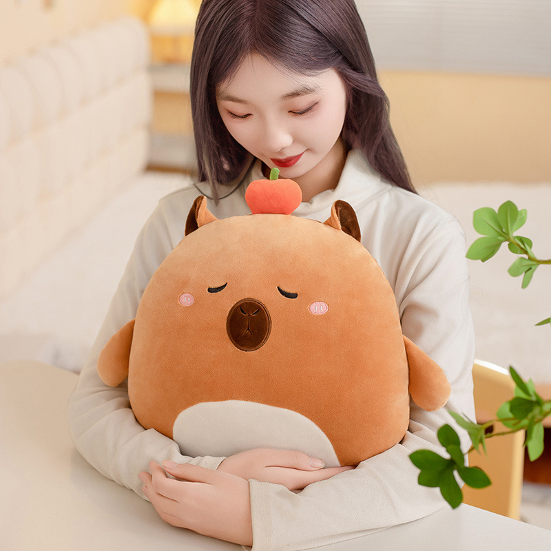 Capybara 36cm hess animal plush pillow with soft plush fabric and rounded shape, shown as a cozy cuddle cushion in a warm bedroom setting