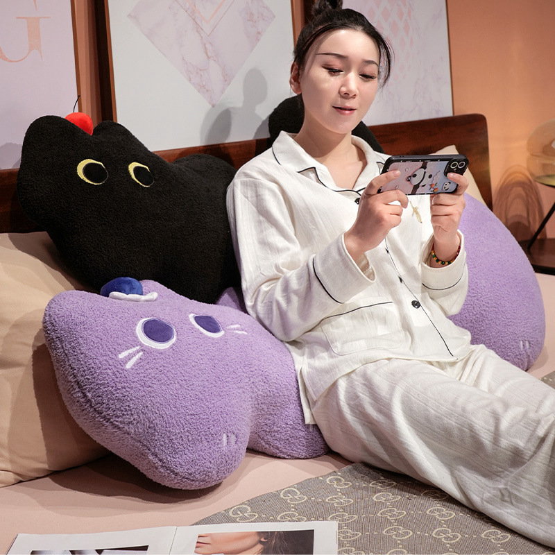 Cloud cat long plush pillow in black and purple, curved plush body cushion used as back support for relaxing and casual lounging in a bedroom setting