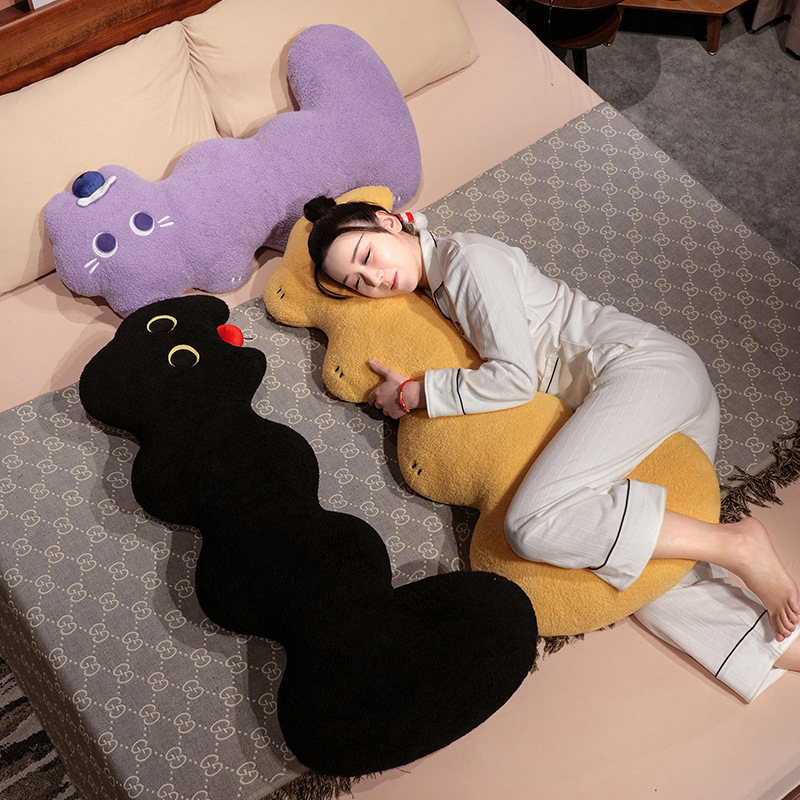 Cloud cat long plush pillow in black, yellow and purple, soft elongated body cushion placed on a bed for hugging, side sleeping and cozy full body support