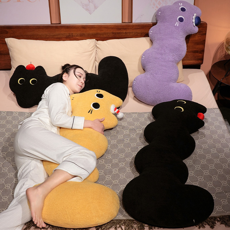 Cloud cat long plush pillow in black and yellow, soft elongated body cushion designed for hugging and side sleeping on a bed in a cozy bedroom setting