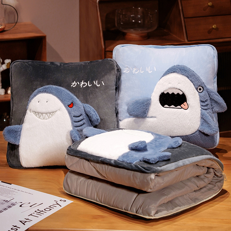 Shark plush pillow blanket in two playful styles with blanket neatly folded inside, highlighting soft plush texture and multifunctional home decor use