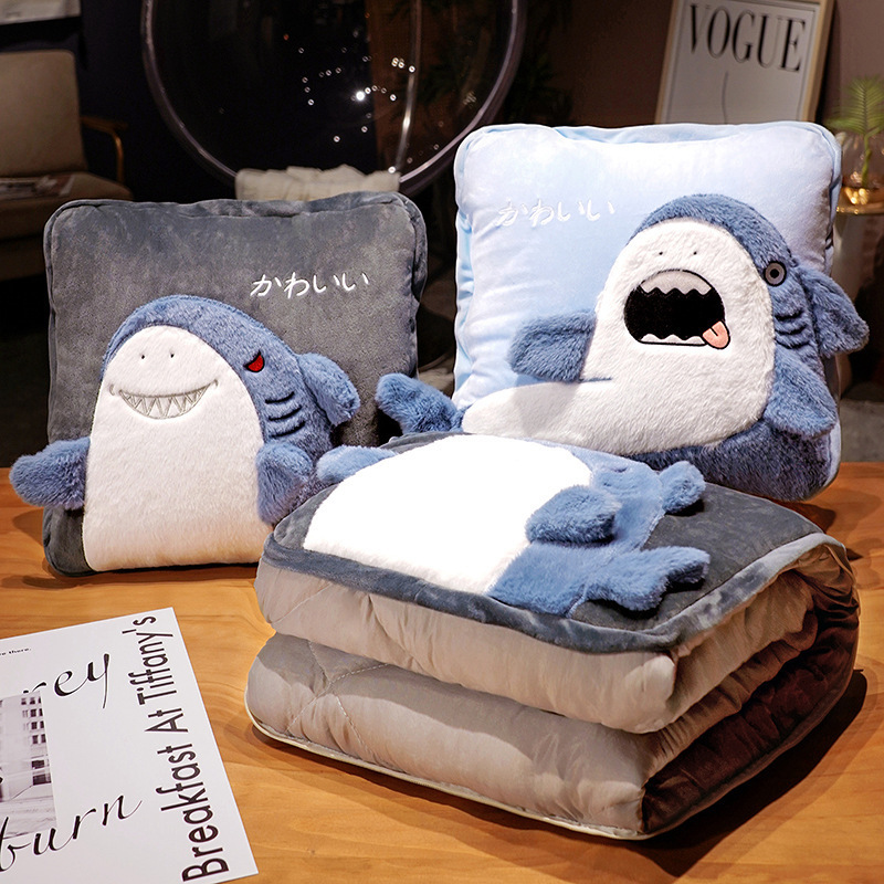 Shark plush pillow blanket in funny and mischievous styles displayed on a table, showing folded blanket stored inside the cushion for compact storage and cozy home use