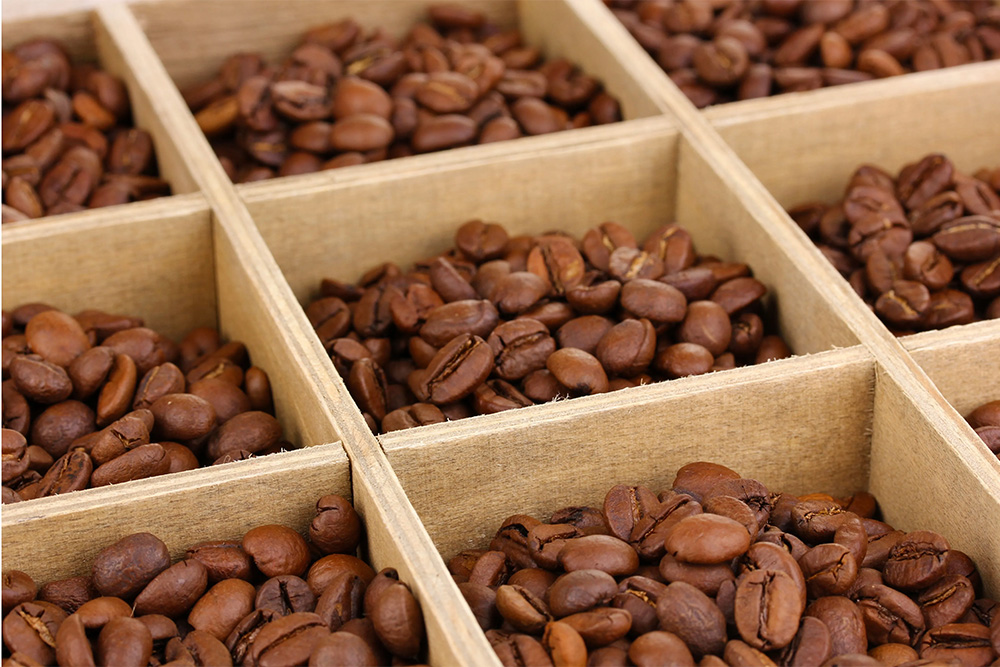 Furama Different varieties of roasted coffee beans inside wooden compartments 