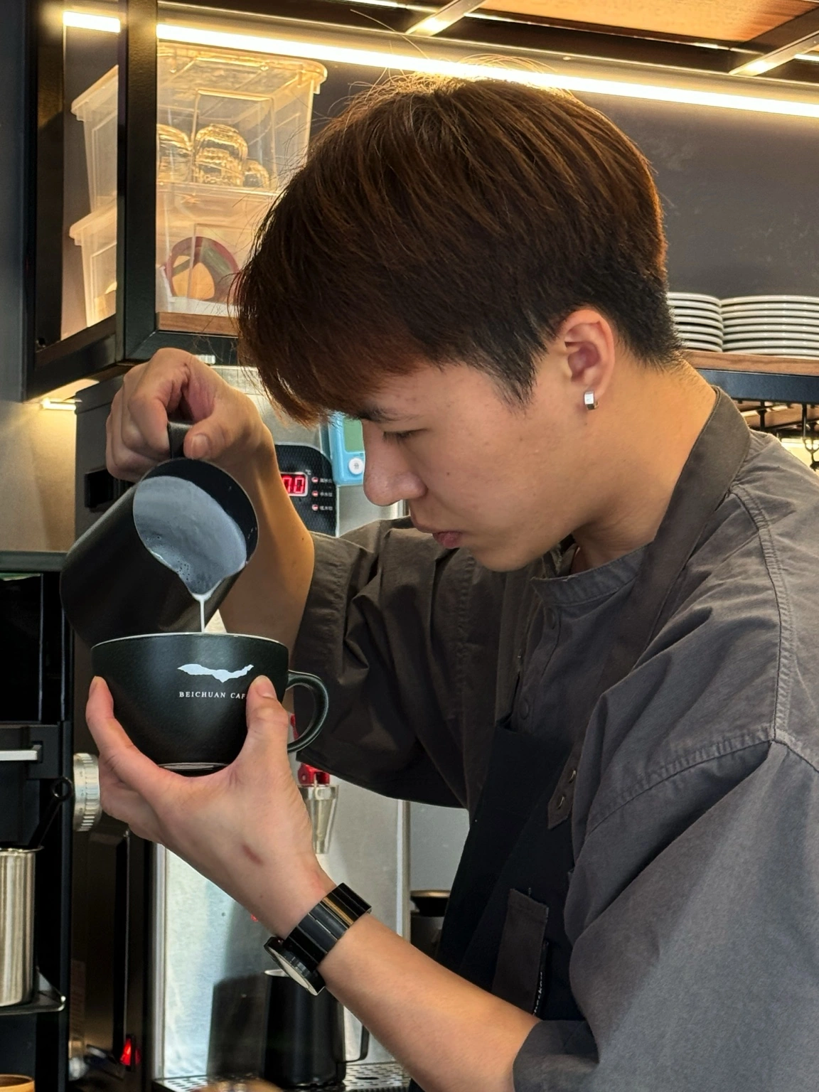 北川咖啡咖啡師以客製杯出杯,注入牛奶做拉花