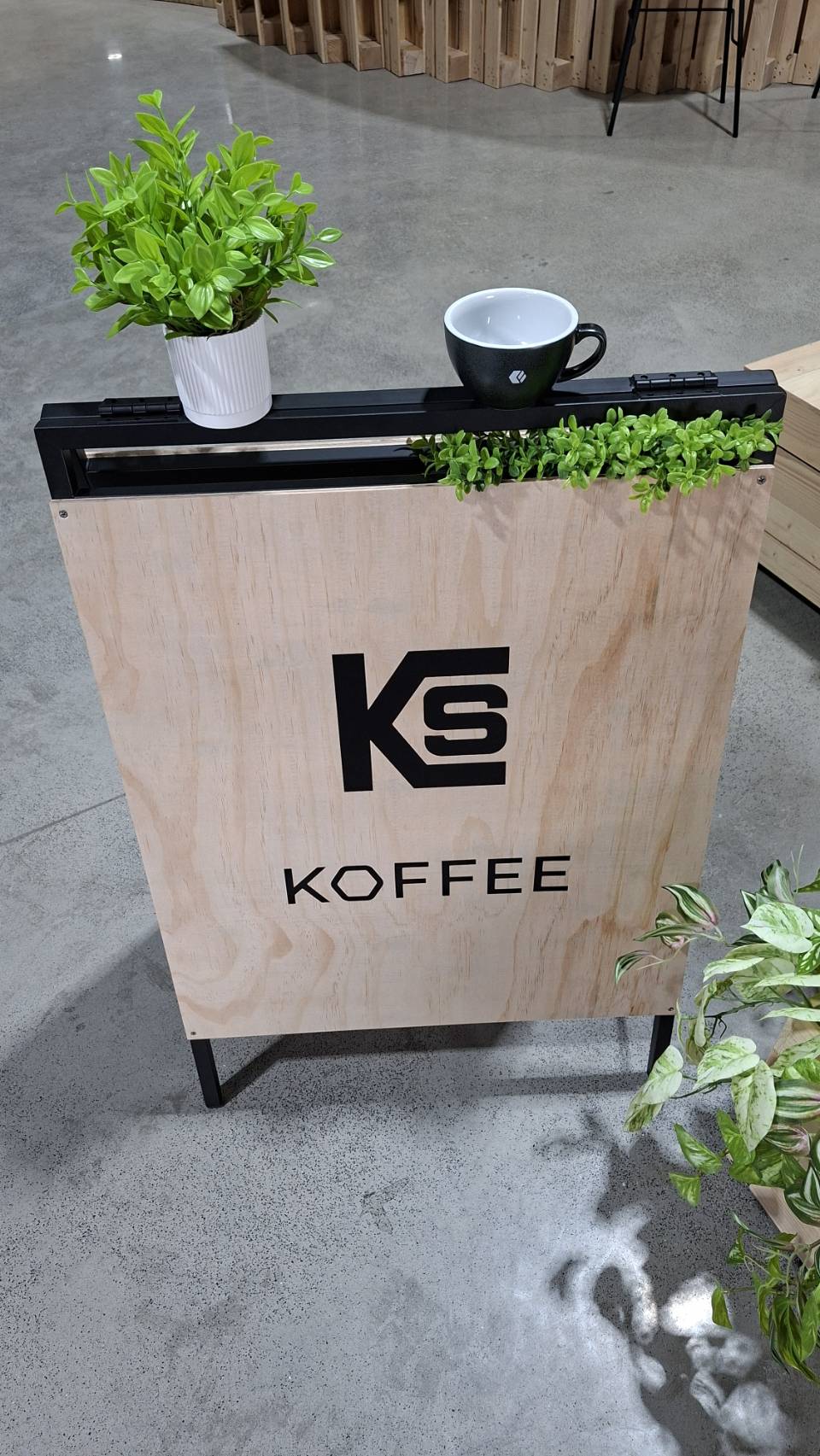 鉅鋼機械公司內的 KS KOFFEE 咖啡角招牌,上方放著一只煤炭灰的 Loveramics 客製咖啡杯