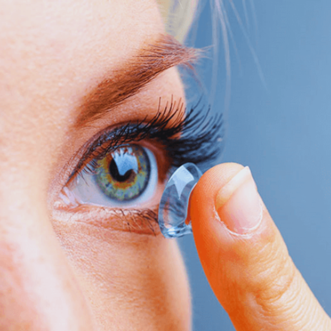 Woman putting contact lens in her eye - Contact Lens Shop