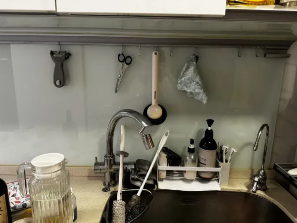 桃園廚房施工前，淺綠色玻璃壁面掛滿吊桿與廚具