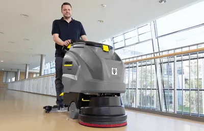 Walk-behind scrubber dryer on a laminate floor Man seen cleaning a laminate floor using a Kärcher walk-behind scrubber dryer