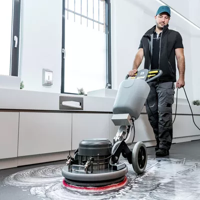 Man seen cleaning a linoleum floor using a corded scrubber dryer. Man seen cleaning a linoleum floor using a corded Kärcher scrubber dryer.