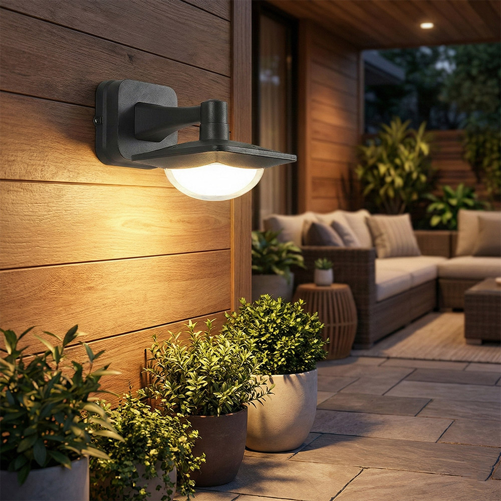 現代黑色戶外壁燈安裝於石砌外牆，照亮別墅庭院用餐區，營造溫馨晚餐氛圍