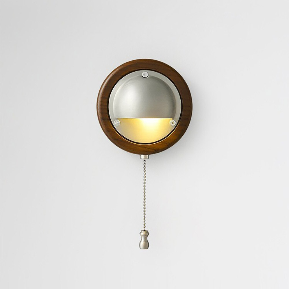 復古圓形木質拉繩壁燈，銀色金屬半圓遮罩散發溫暖黃光，安裝於白色牆面，展現中世紀現代風格家居設計。