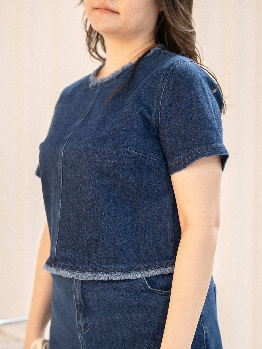 Fray-edged denim blouse designed to flatter mid-size and plus-size silhouettes