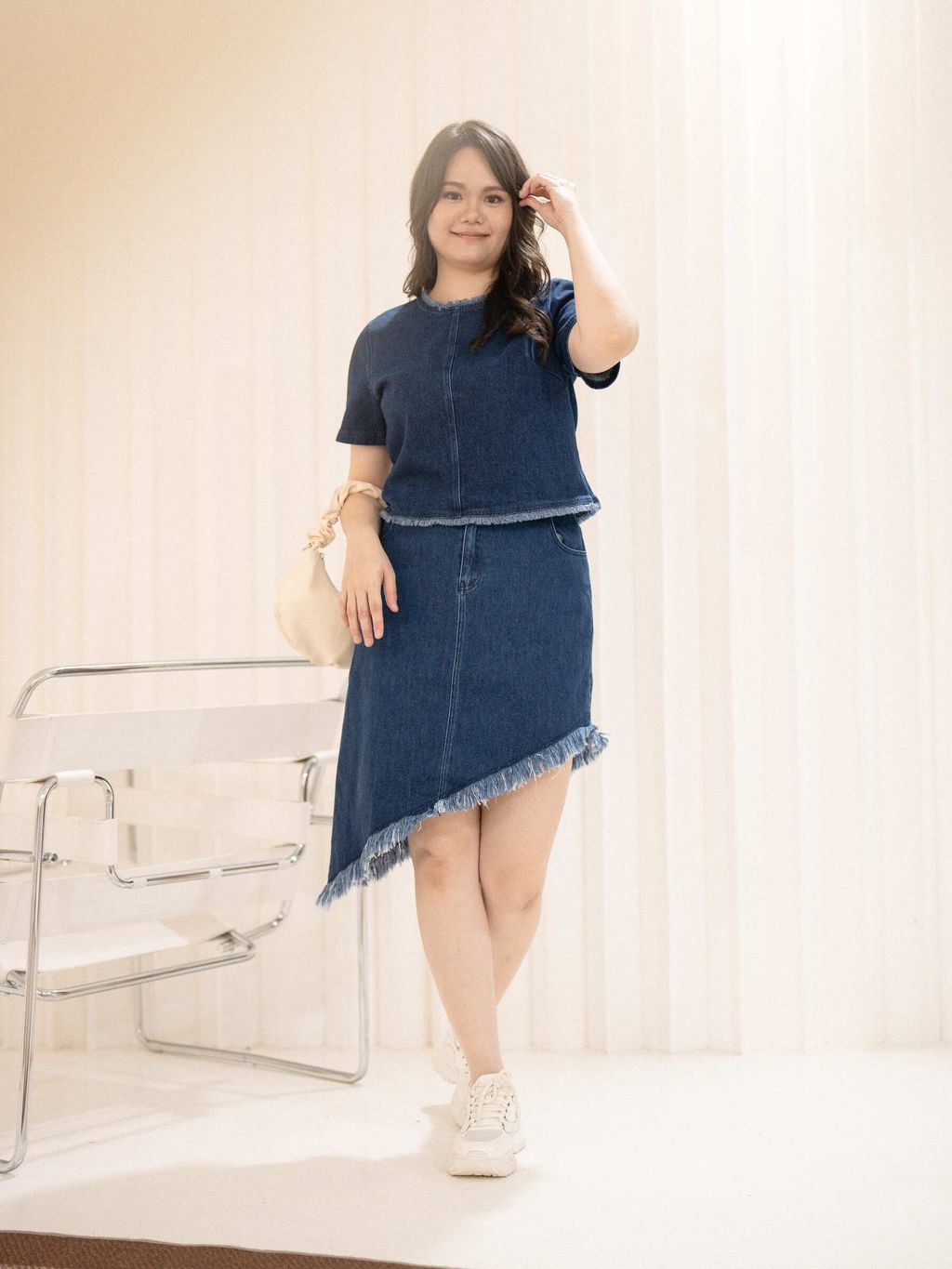 Plus-size model wearing denim top with frayed neckline and clean front seam