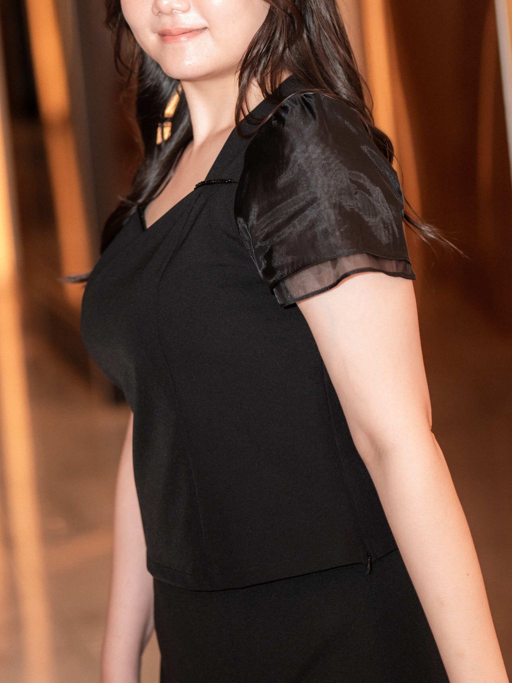 Close-up of black puff sleeve blouse featuring sheer sleeve texture and flattering waist fit for plus-size women.