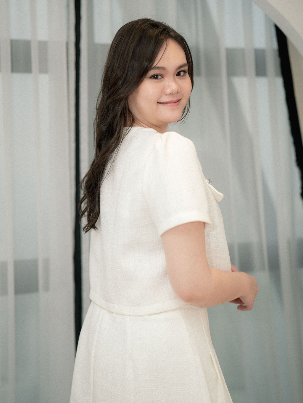 Back view of plus-size model in short-sleeve white tweed blouse with a tailored fit