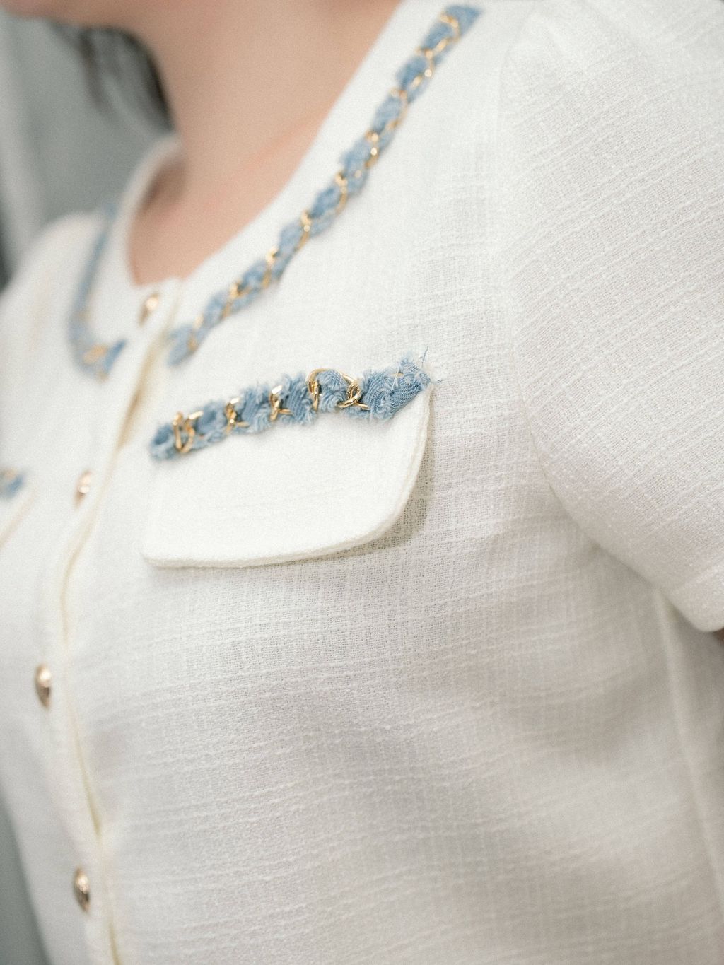 Detailed shot of blue frayed trim and gold chain on collar and chest pockets