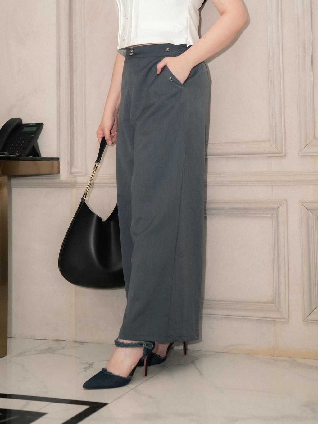 Side view of plus-size wide leg pants featuring a high waist, smooth side seams, and decorative metallic buttons near the pocket—offering a sleek, flattering profile.