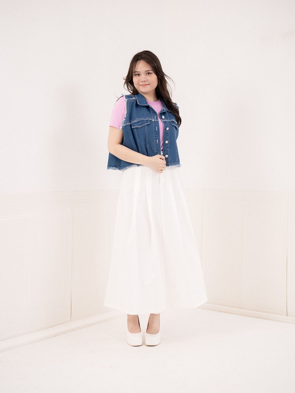 White midi skirt paired with cropped denim vest and pink top – chic layering.