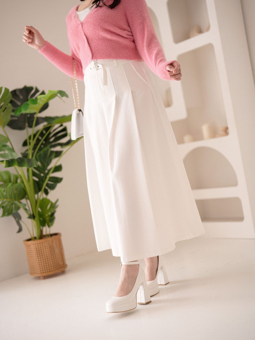Close-up of belted waistband and side pleats on white midi skirt.