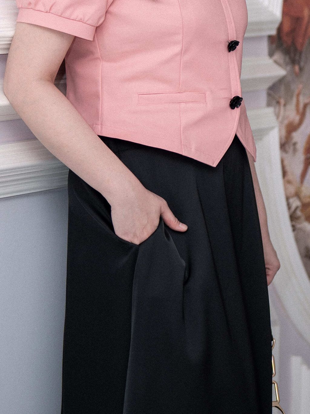 Black satin skirt with fluid drape and discreet side pocket detail.