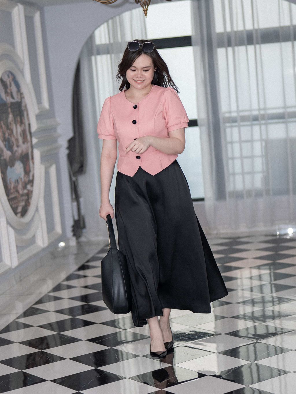 Elegant black satin A-line skirt styled with heels and a handbag.