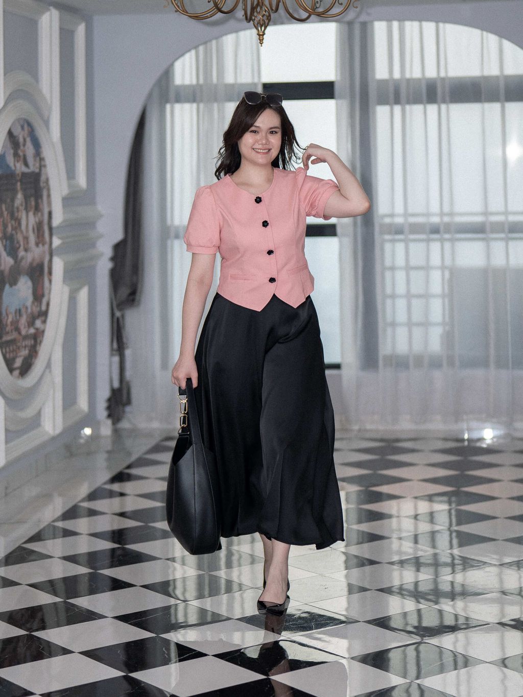 Plus-size woman wearing a black satin midi skirt with a pink structured blouse.