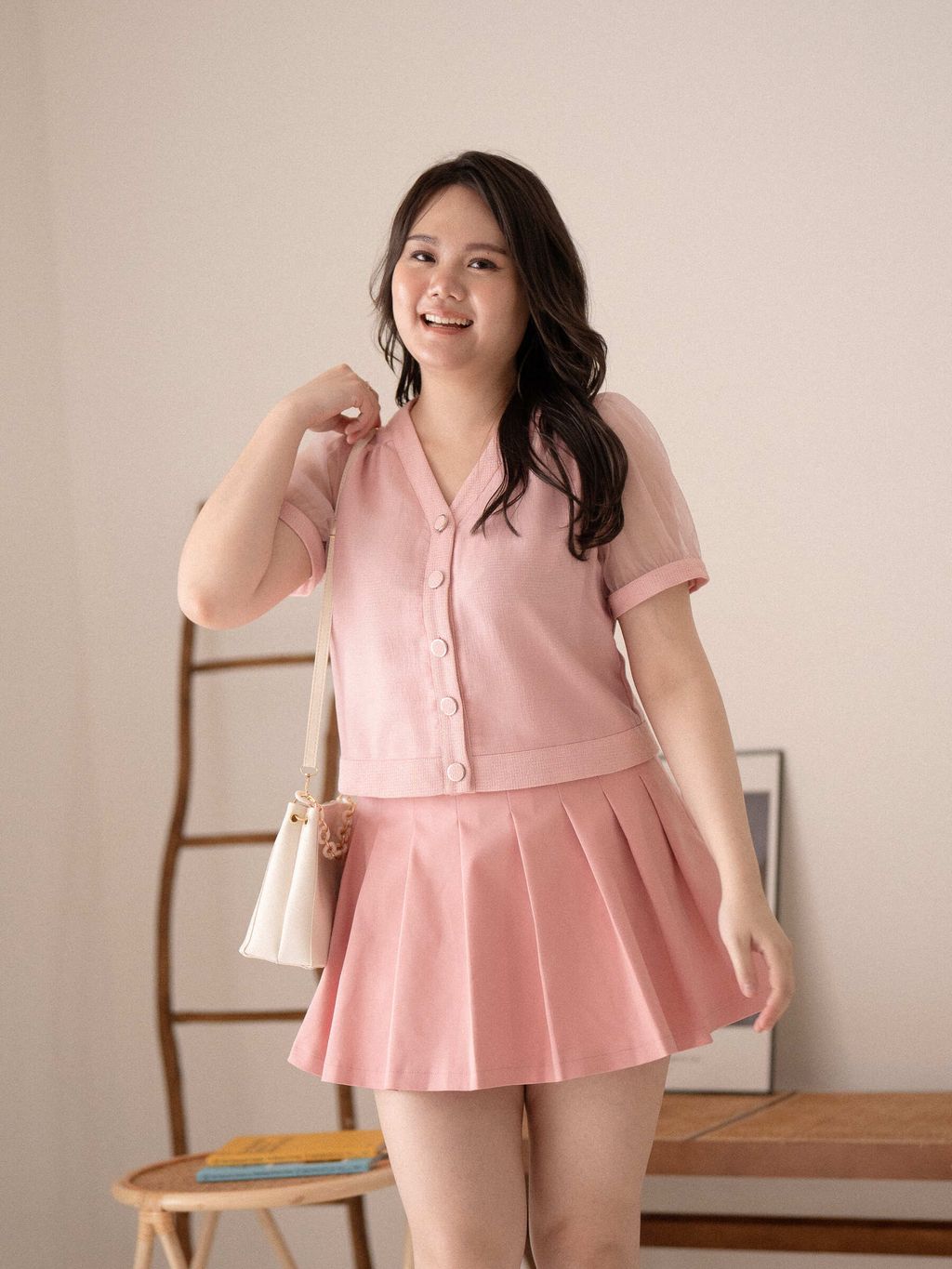Youthful plus-size look with pink pleated skirt and sheer puff-sleeve top